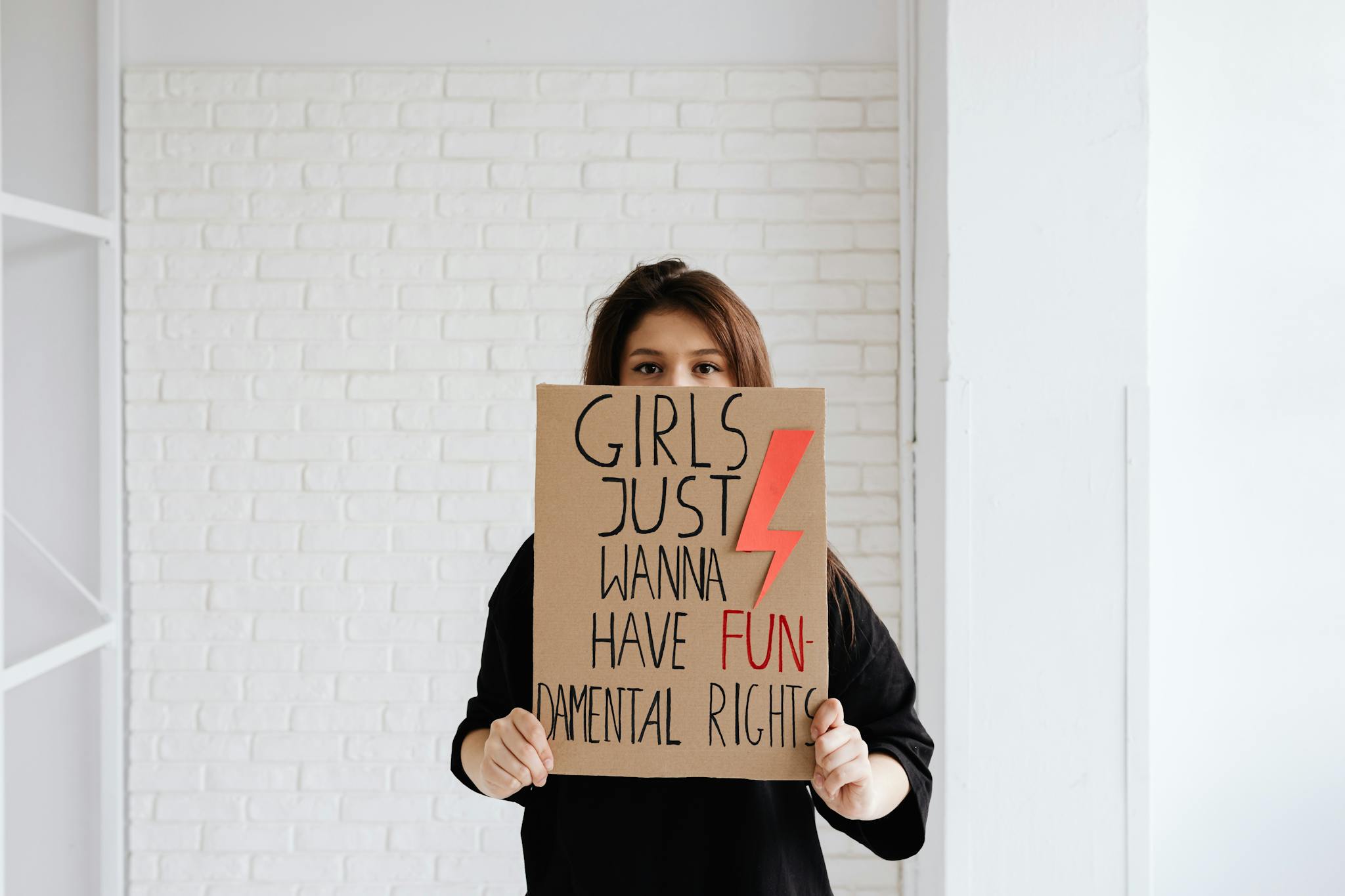 Woman holding a sign advocating for women's fundamental rights indoors.
