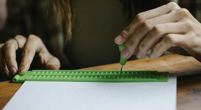 Crop anonymous person with vision loss writing braille letter with slate and stylus